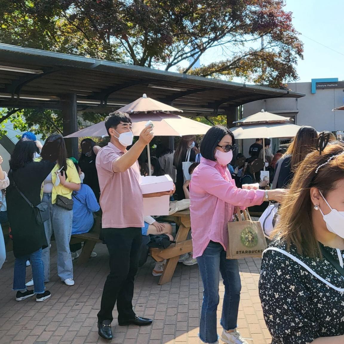 Hình ảnh bố mẹ GOT7 đứng phát bánh gạo cho fan trong khu vực tổ chức concert (3)