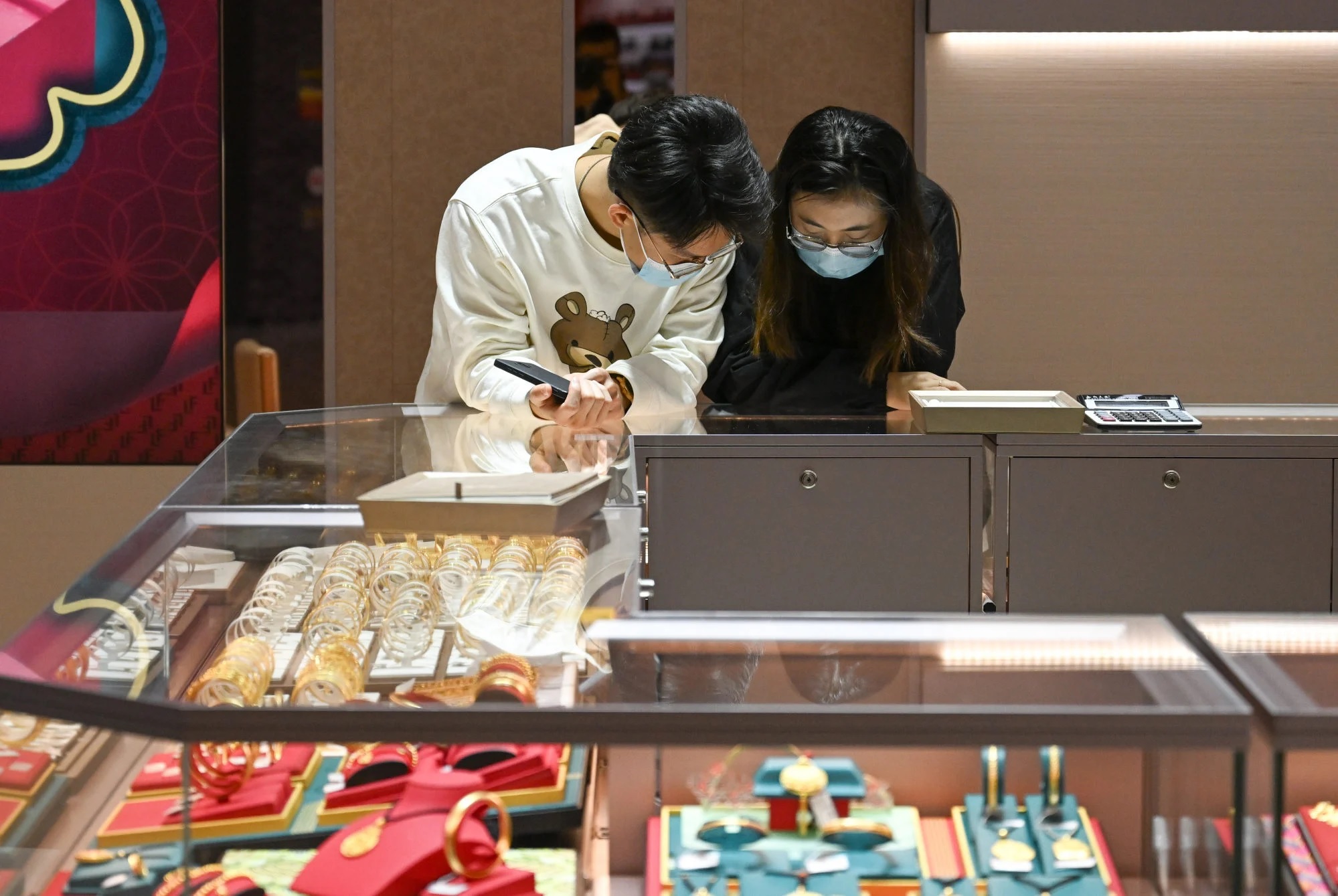  Các khách hàng trẻ tuổi lựa chọn sản phẩm trong một cửa hàng trang sức miễn thuế ở Hải Khẩu,   ...