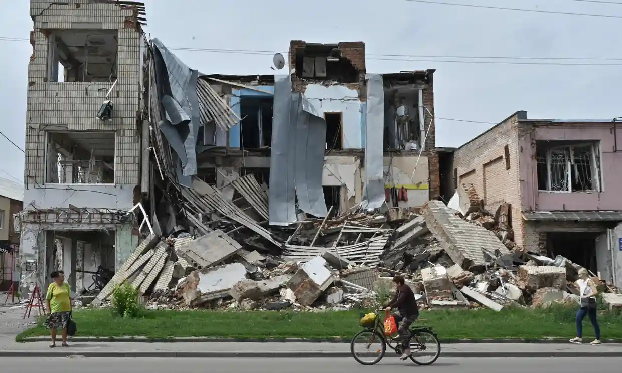 Người đi bộ đi ngang qua một cửa hàng bị phá hủy ở thành phố Okhtyrka, Ukraine.