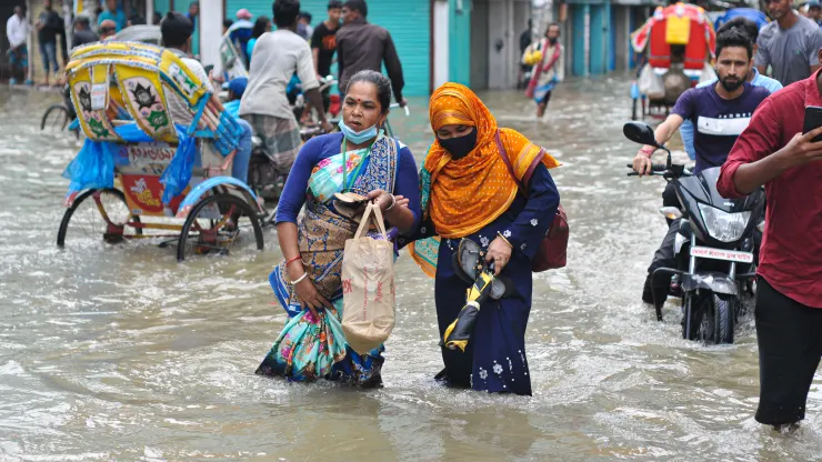 Người dân lội qua dòng nước lũ, ngày 17/5/2022 ở Sylhet, Bangladesh. Nhiều con đường ở Sylhet ...