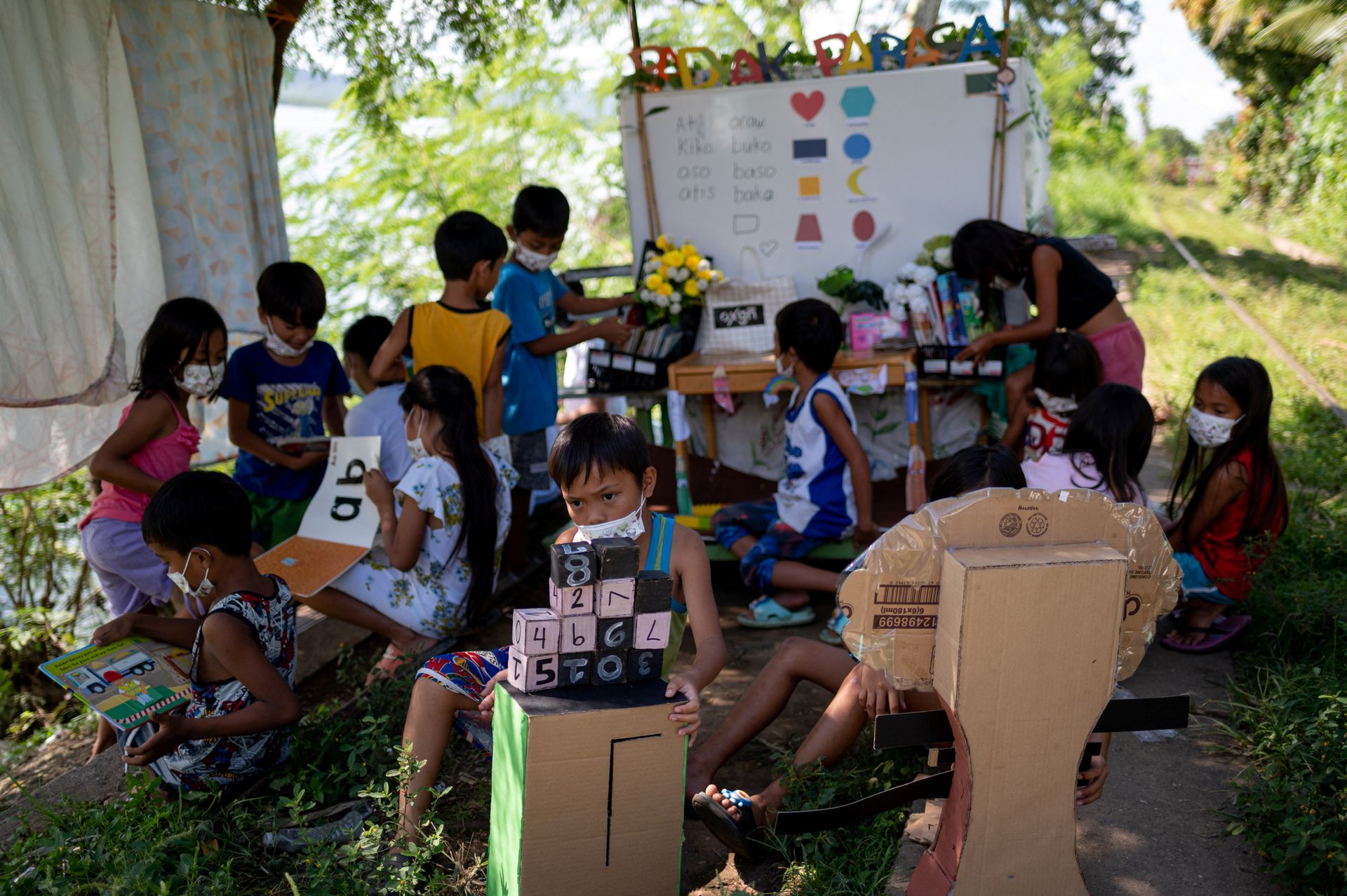 Các em học và tập đọc bằng những dụng cụ, sách vở chiếc xe đẩy chở tới (Ảnh: Reuters)